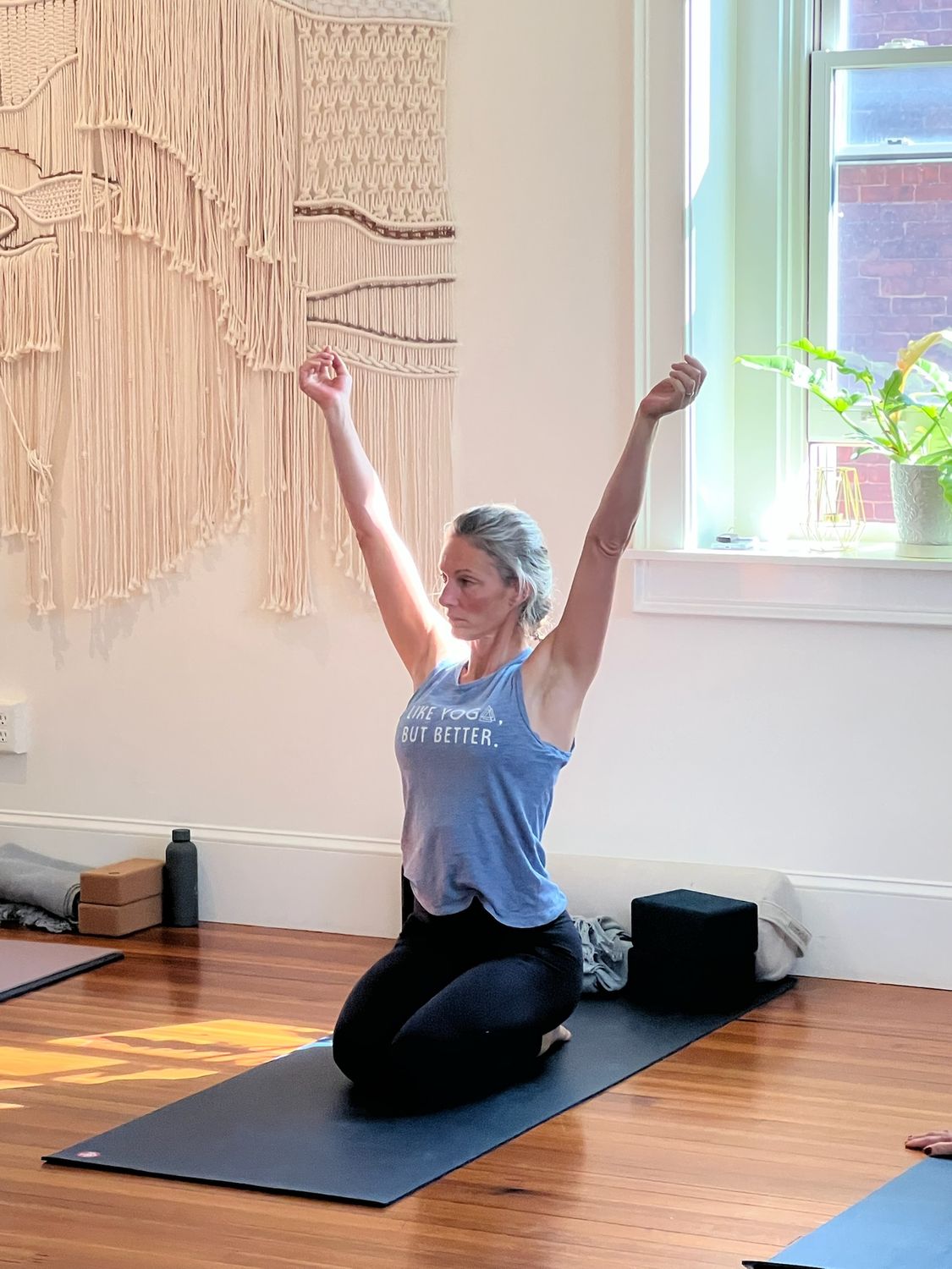 a student kneeling on her mat, arms raised in celebration